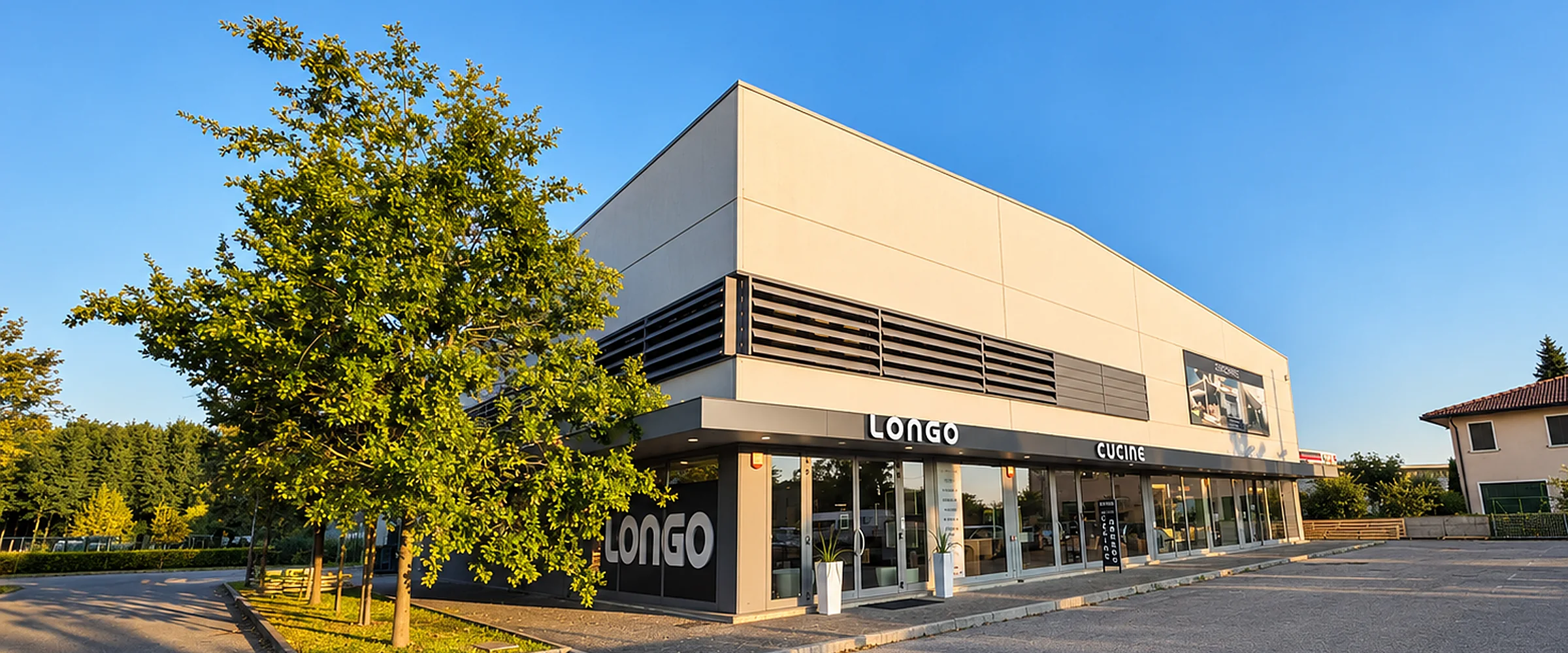 Lo showroom Longo Design a Noale visto dal parcheggio: edificio bianco con l'insegna LONGO, ingresso a vetrate e albero in primo piano